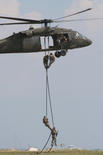 A US Army Blackhawk helicopter deploys US Army Rangers by fastrope.