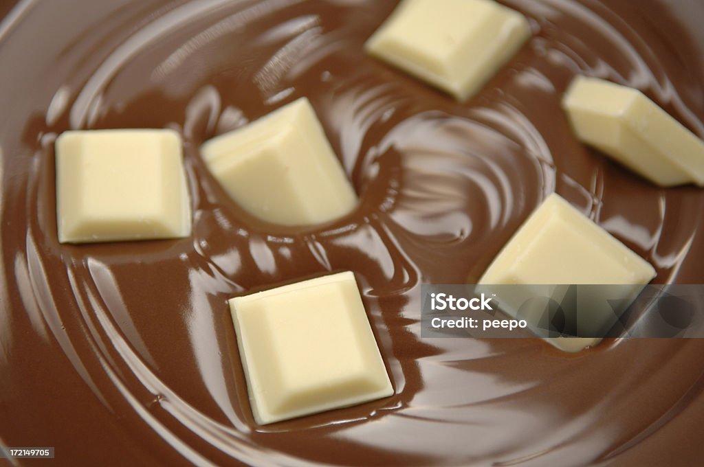 Primo piano di cioccolato bianco di fusione di cioccolato al latte. - Foto stock royalty-free di Cioccolato bianco