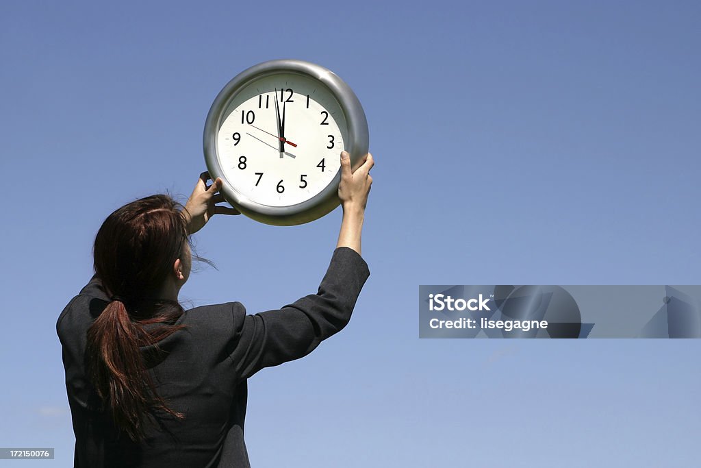 Zenith Woman holding a clock against a clear sky at noon. 12 O'Clock Stock Photo