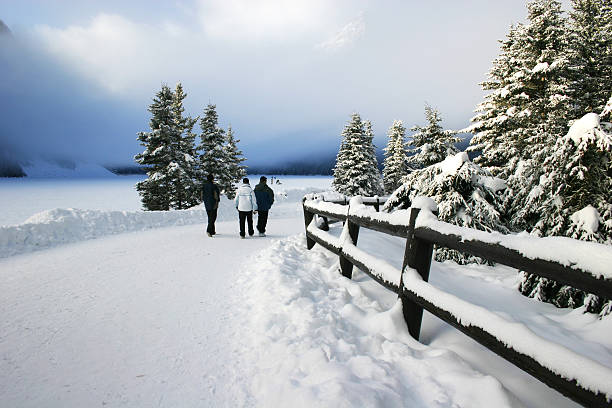 tres los turistas a pie en camino cubierto de nieve en lake louise - lago louise lago fotografías e imágenes de stock