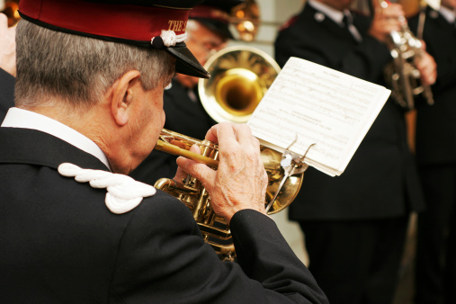 A marching band instrument at a public parade in summer. A person playing tuba, part of a marching band.