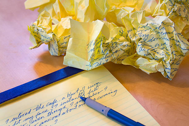 the hand of a man writing in a blank book beside a book background