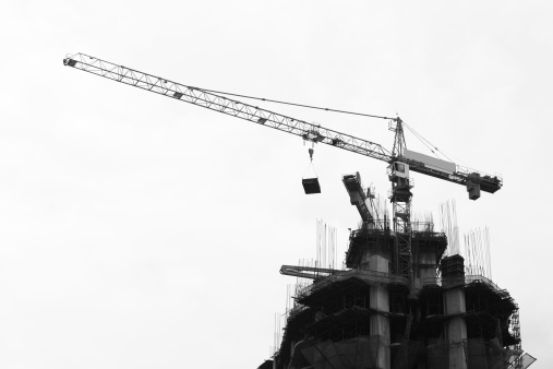 Construction crane and building under construction, in black and white.