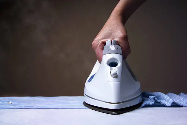 A steam iron ironing a shirt.