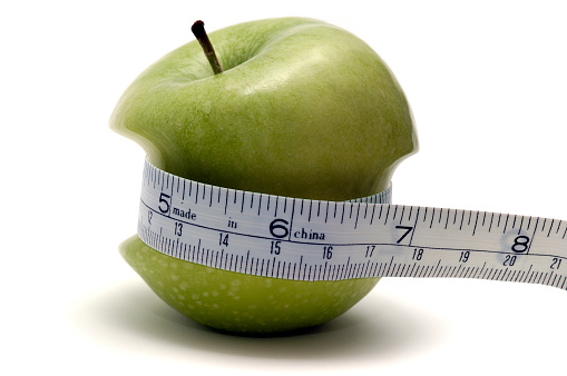 apple squeezing it's waist while being measured. dieting.
