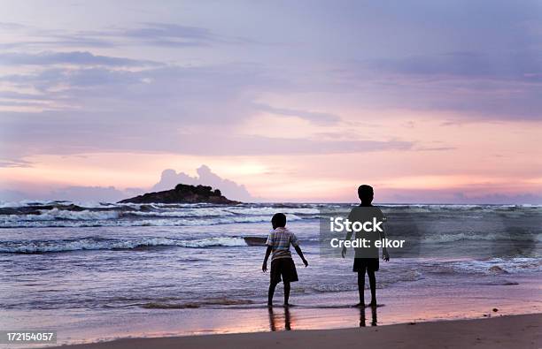 Ragazzi Guardando Il Tramonto Su Una Spiaggia - Fotografie stock e altre immagini di Acqua - Acqua, Adolescente, Ambientazione esterna