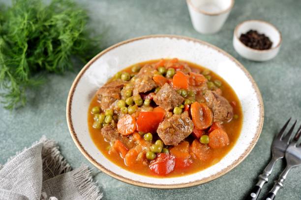 Stewed beef with carrots, bell peppers and green peas stock photo
