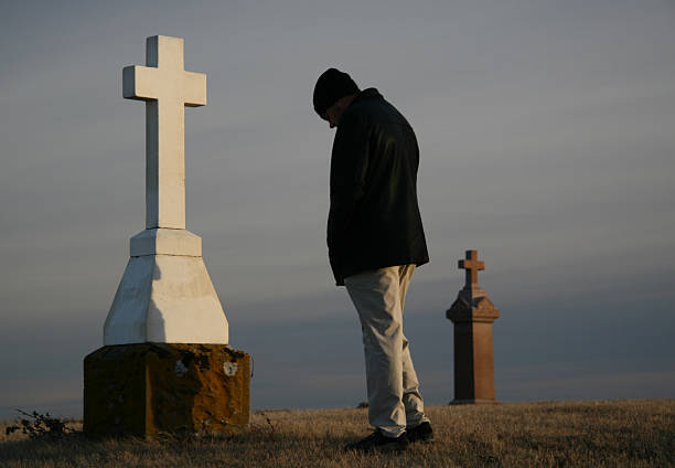 istock A man bows his head at a grave marker. 172154464