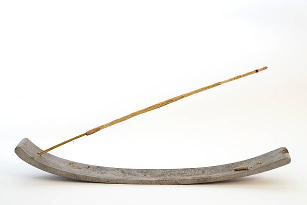 An incense stick burning on a curved plank incense stick, white background incense photos stock pictures, royalty-free photos & images