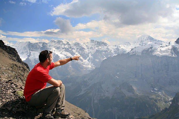 homem sentado no topo da montanha e apontando uma direção - handcarves nature sports and fitness people imagens e fotografias de stock