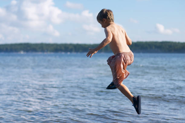 istock Boy in shorts jumping mid-air into lake 172156852