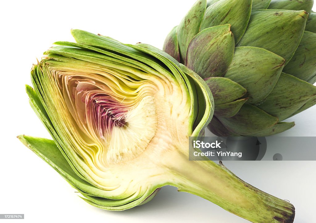 Artichoke Heart, Half Cut Open Vegetable Plant on White Background Two artichokes. The plant in the foreground is cut in half to display the artichoke heart. The vegetable flower in the background is whole. Shown on a white background. This food may be grown on an organic farm and is an ingredient for gourmet meals. It may be part of a vegetarian diet. Artichoke Heart Stock Photo