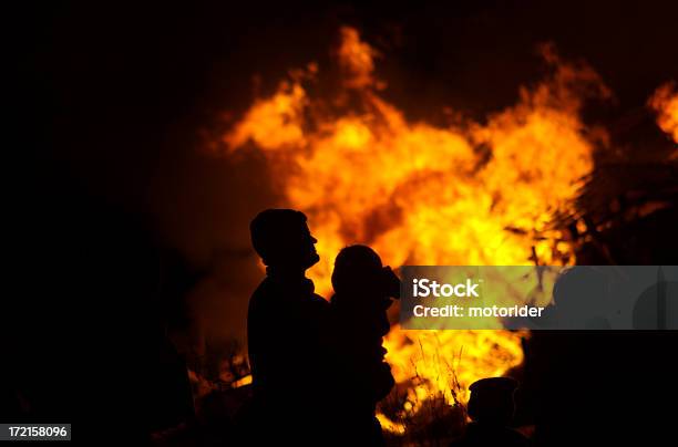 Padre Carying Bambino Con Fuoco Sfondo - Fotografie stock e altre immagini di Falò - Falò, A mezz'aria, Accudire