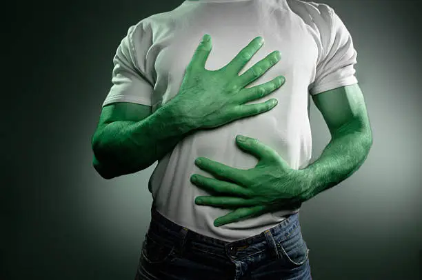man with green skin holding chest and stomach