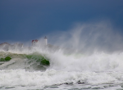 Nubble lighthouse behind stormy seas in York, Maine