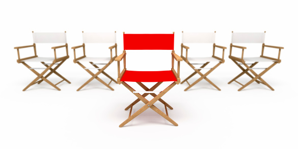 Four white & one red director's chairs. Focused on red one.