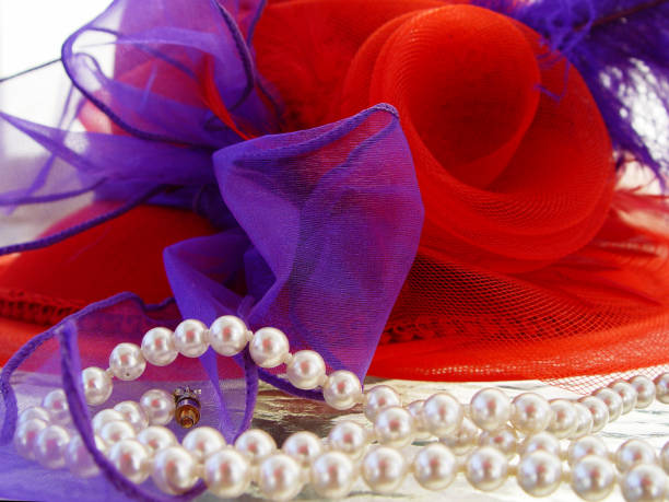 On a black glossy background are pearl beads on a silver chain. The front part of the beads is in focus.