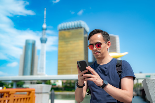 Hispanic male tourist standing against broadcasting Tokyo Skytree observation tower in Japan