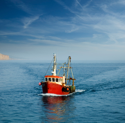 Small fishing boat with nets follows the sea surface of the Mediterranean Sea view from above aerial away distance