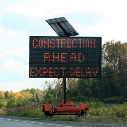 Portable solar powered highway sign indicating construction ahead expect delay.