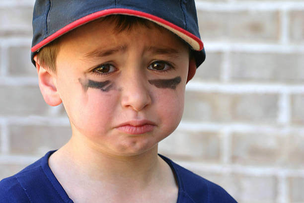 Crying young boy with black marks on his face stock photo