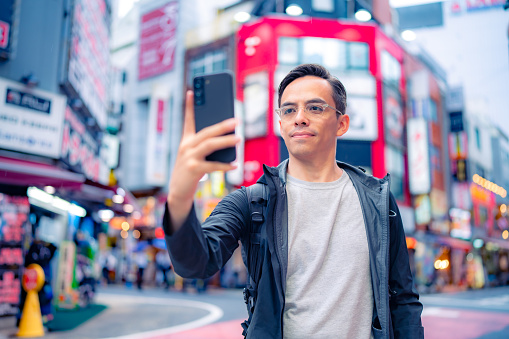 Hispanic male in casual clothes taking selfie in Shinjuku neighborhood in Tokyo, Japan