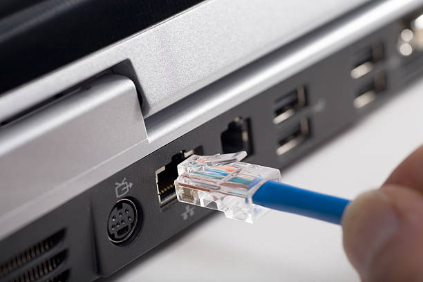 Fingers plugging usb cable into back of laptop closeup image of hand plugging ethernet cable into laptop web browser photos stock pictures, royalty-free photos & images