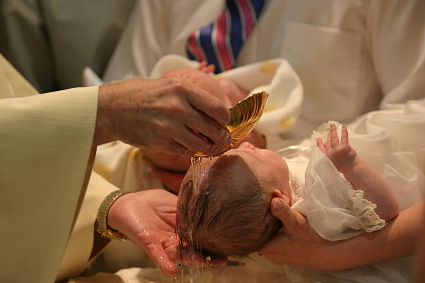 Baptism Close up of baby girl being baptized. Hands of priest and God parents visible; water clearly visible flowing over baby's head. (Twin brother in background.) baptism photos stock pictures, royalty-free photos & images