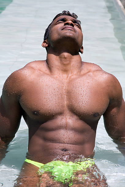 abs and arms supporting hunky guy sunworshipping  in pool stock photo