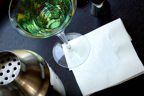 Martini with blank napkin A horizontal close-up shot of an apple martini, shaker and a white cocktail napkin with some nice blank space for your personalized message.  napkin stock pictures, royalty-free photos & images