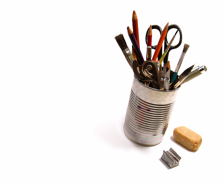 A bunch of art supplies jumbled up in a tin can