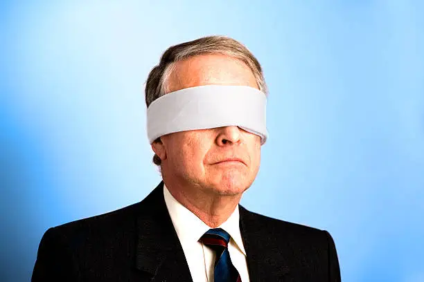 A senior businessman with a blindfold on.