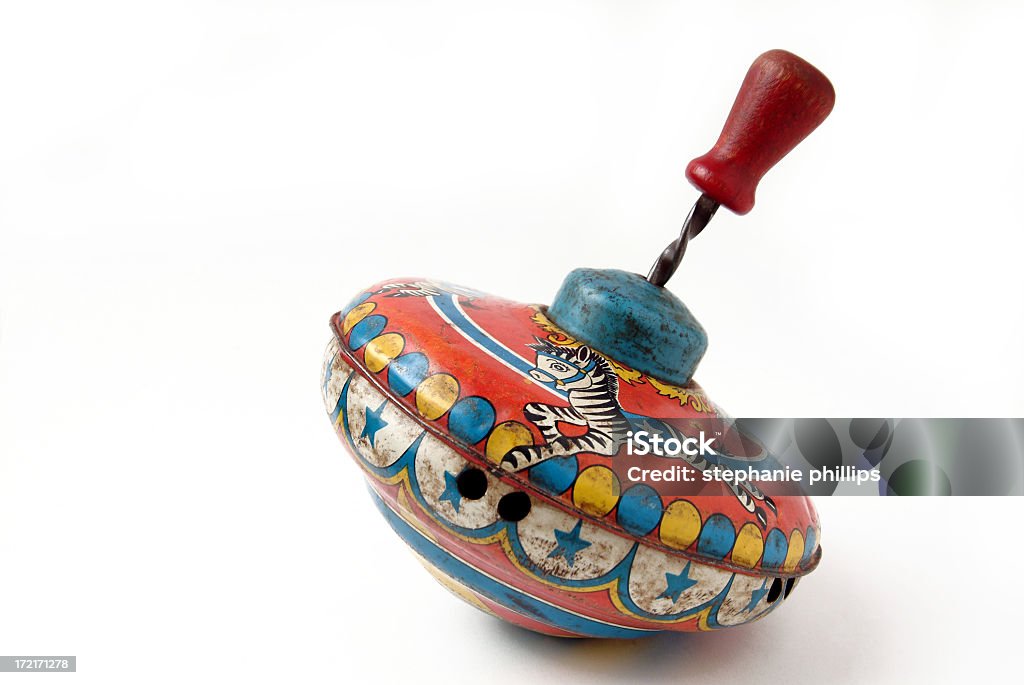 Antique Brightly Painted Metal Child's Toy Spinning Top Studio image of a very old metal spinning top photographed on a white background. The top is brightly painted with a merry go round theme. The paint is very worn and the top has some dents. Toy Stock Photo