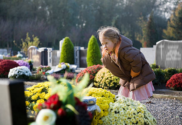 Sad young girl at the graveyard, praying stock photo