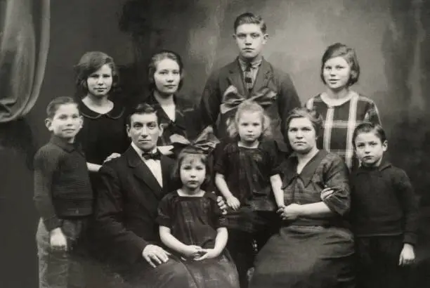 "Big family posing for a photograph in the twenties. Two parents, eight children."