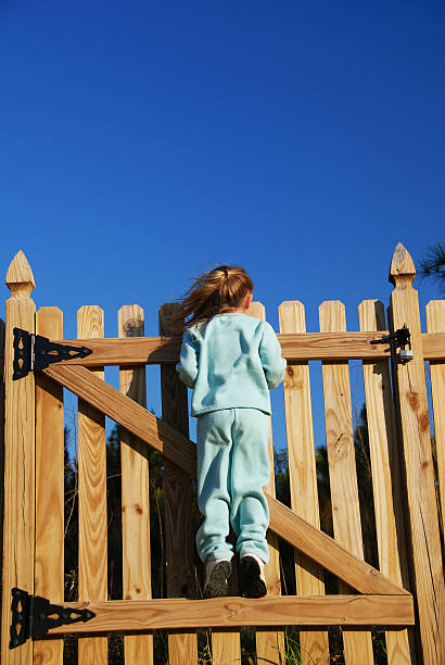kleines mädchen über zaun - fence child neighbor peeking stock-fotos und bilder