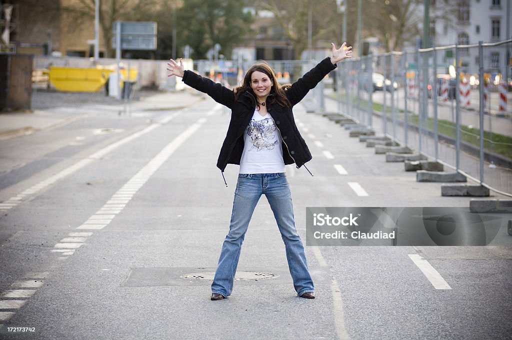 Stop here "Young woman is standing in the middle of the road, raising up her arms.Click on the banners below, and you find similar pics of that model and other women:" 20-24 Years Stock Photo