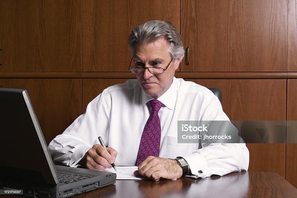 Number Crunching Businessman Photo of a mature financial planner hard at work. Desk Stock Photo