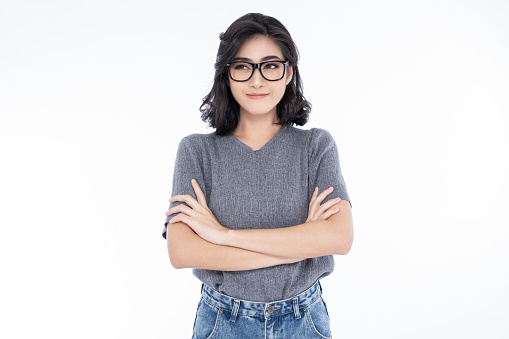 Portriat of Beautiful young Asian woman wearing eyeglasses, looking away and standing isolated on white background. Proud student Korean girl smile and crossed arms head shot portrait.