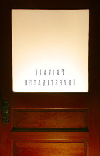 Woden door with a frosted glass panel marked Private Investigaor