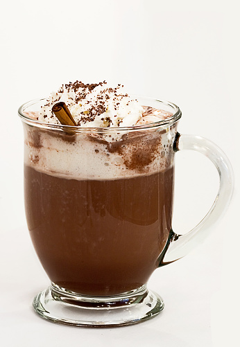 Rich, chocolate drink topped with whipped cream, chocolate shavings, and a cinnamon stick.