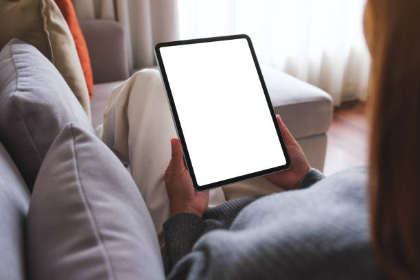 istock Mockup image of a woman holding digital tablet with blank desktop screen while lying on a sofa at home 1721789208