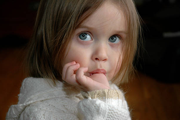 A little girl sucks on her thumb.