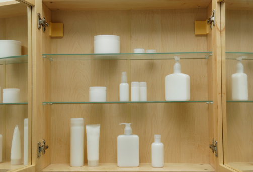 various blank generic cosmetic bottles in wooden and glass cabinet