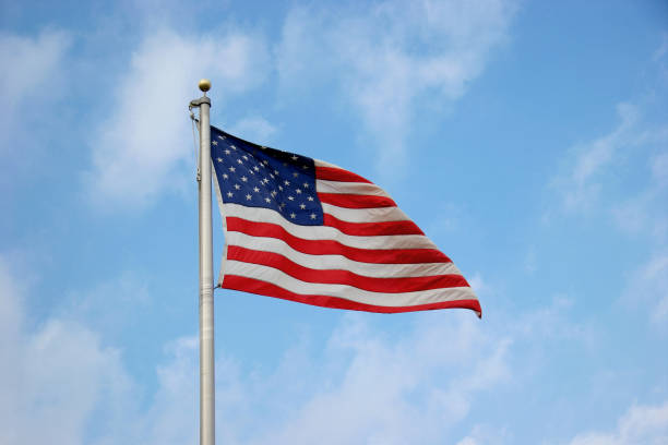 istock American Flag Against Lightly Clouded Blue Sky 172180824