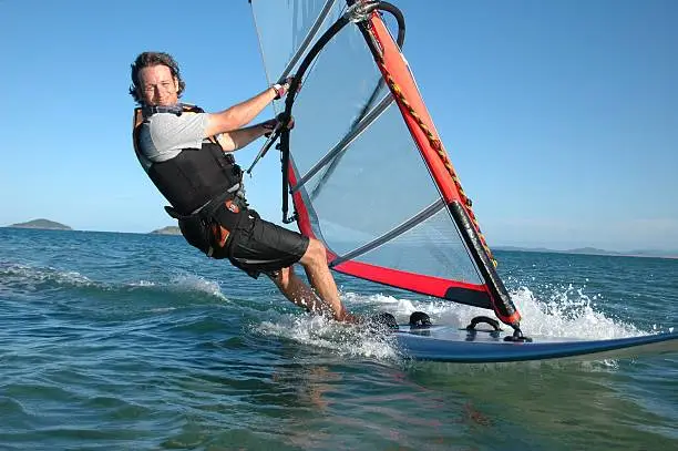 Young man having fun windsurfing on a beautiful sunny day. Click to see more...