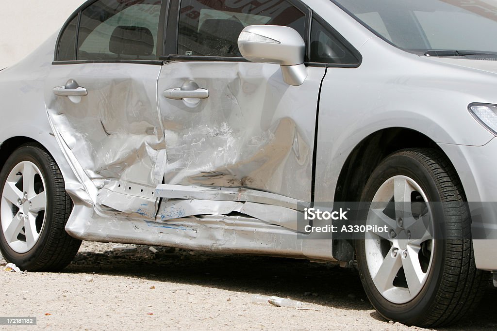 Silver car with a large dent in the side, ruining two doors Side impact crash. Car Stock Photo