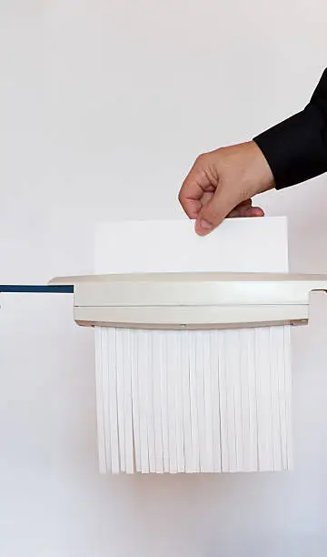 Shredding blank sheet of white paper. Male hand inserting a white page into a shredder.