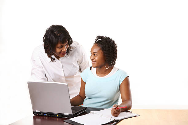 Mother helping her daughter with her homework on a computer stock photo