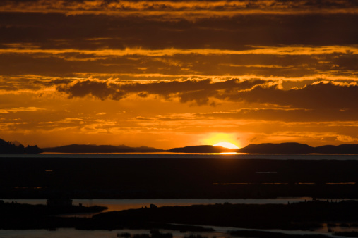 Subject: Sunrise over Lake Titicaca, with the floating islands of the indigenous villages in the foreground.